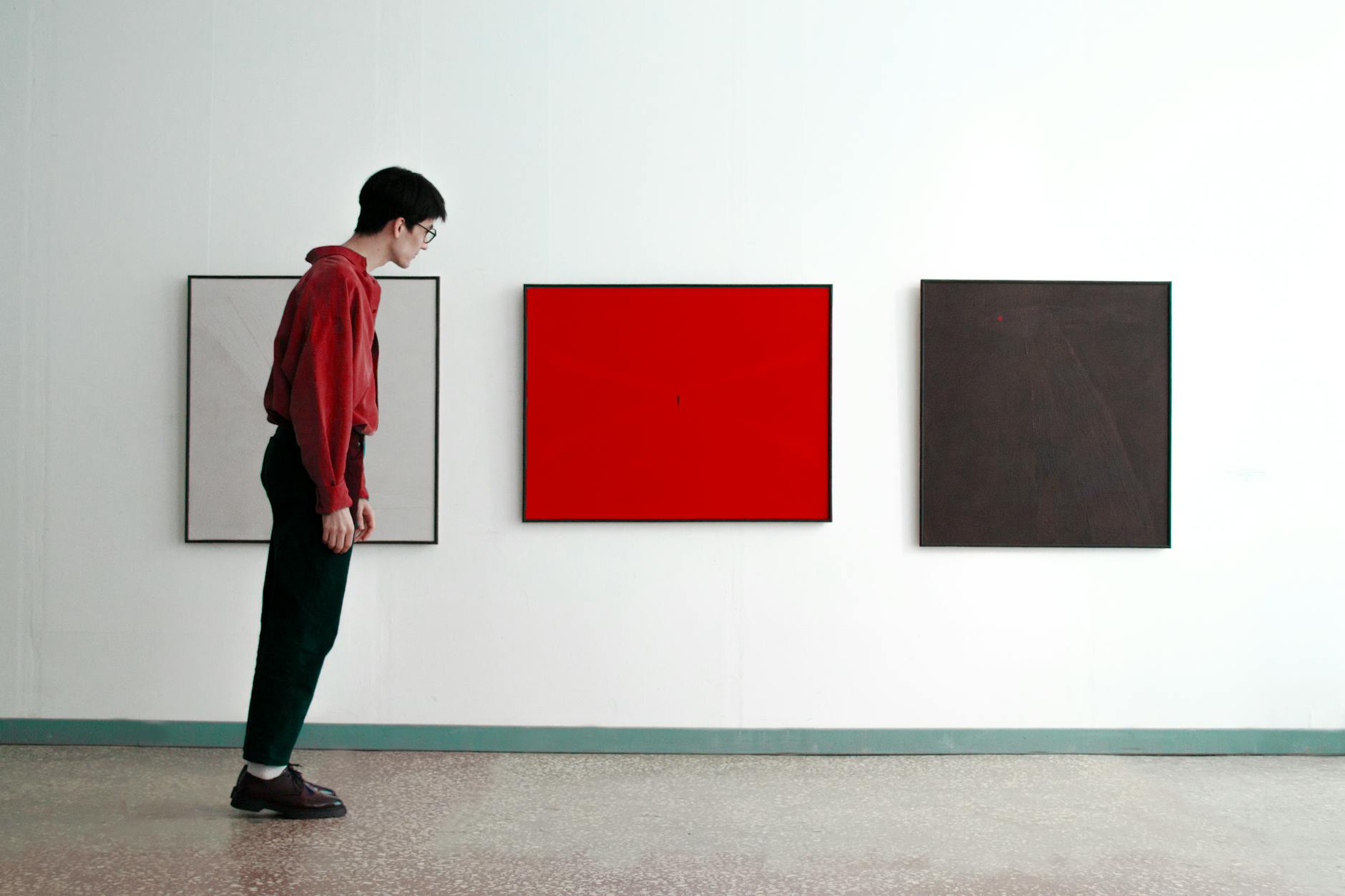 man standing tilted and looking at modern art pictures